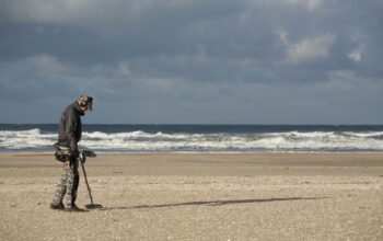 man in black jacket and black pants holding black dslr camera on beach during daytime