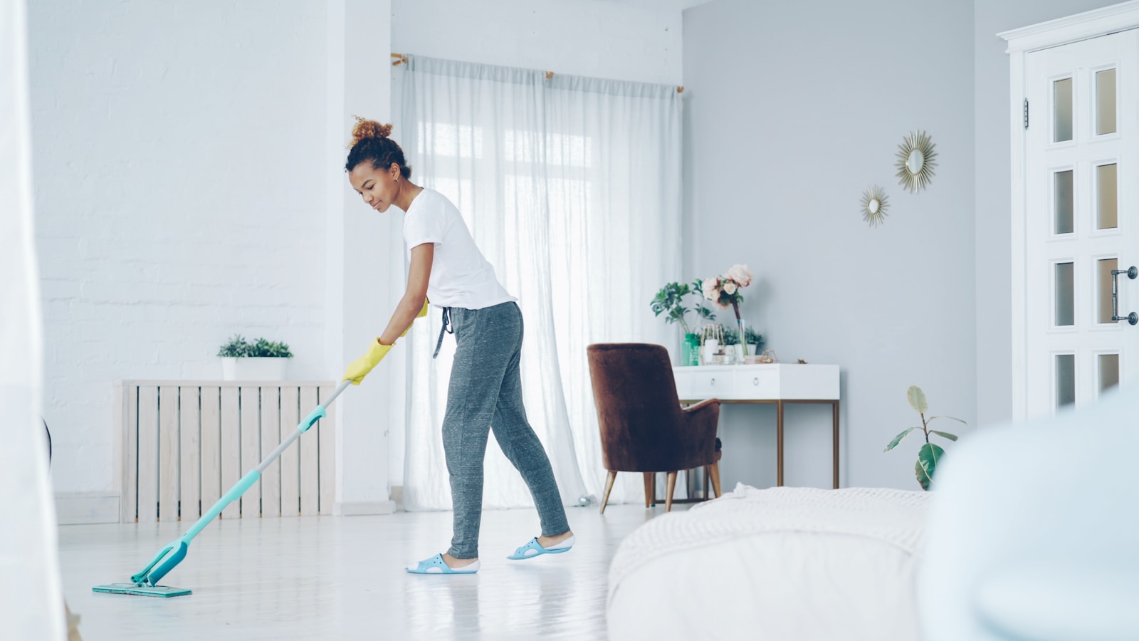A woman mops a bright, modern living room floor.